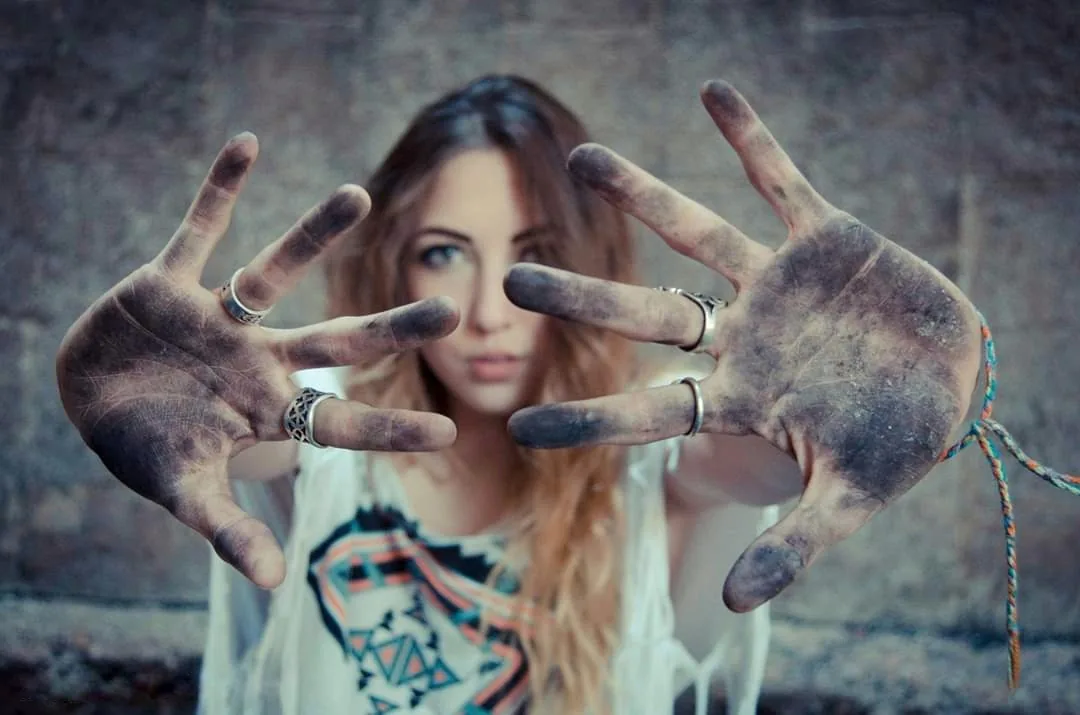 The artist holding up both hands, palms dusted with charcoal